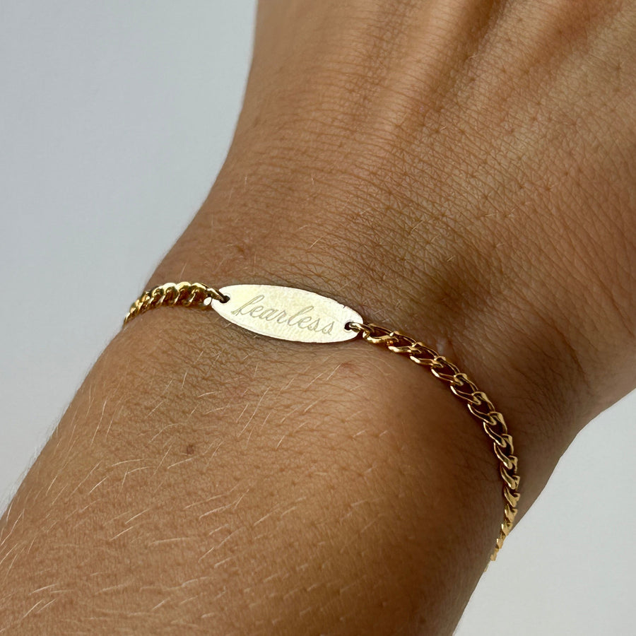 Gold bracelet on a wrist with a plain background