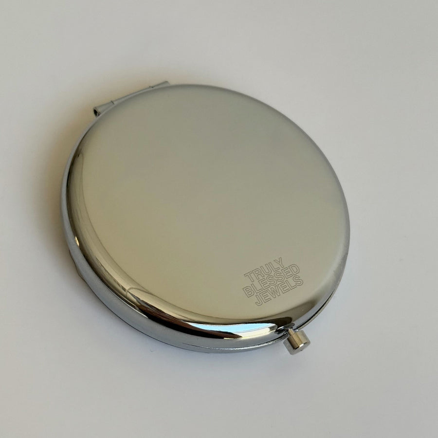 Round metallic compact mirror on a white background