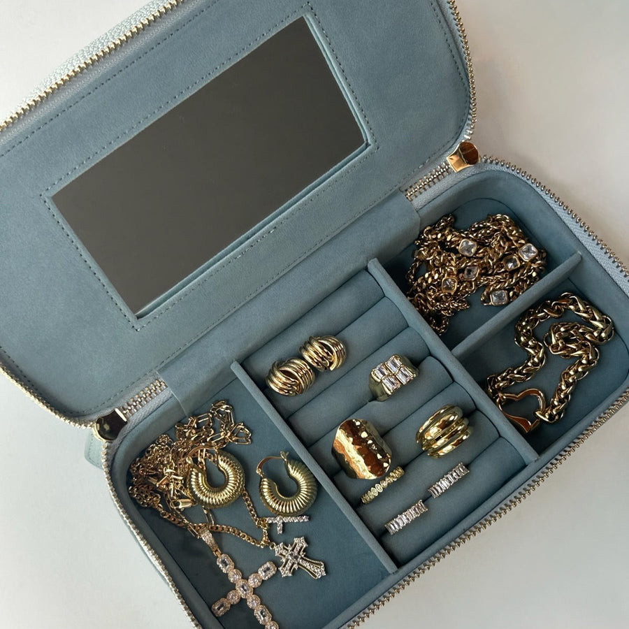 Open jewelry case with gold jewelry on a white background