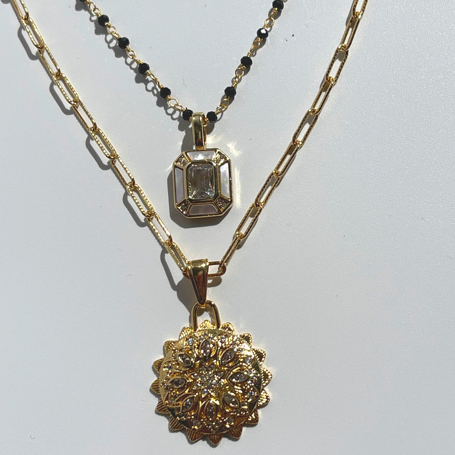 Two gold necklaces with pendants on a light gray background